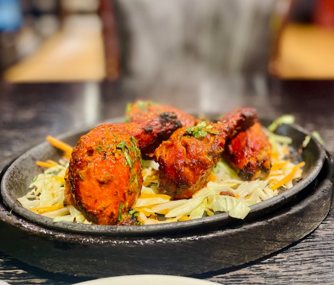 Tandoori chicken arriving on a cast-iron sizzler over shredded cabbage
