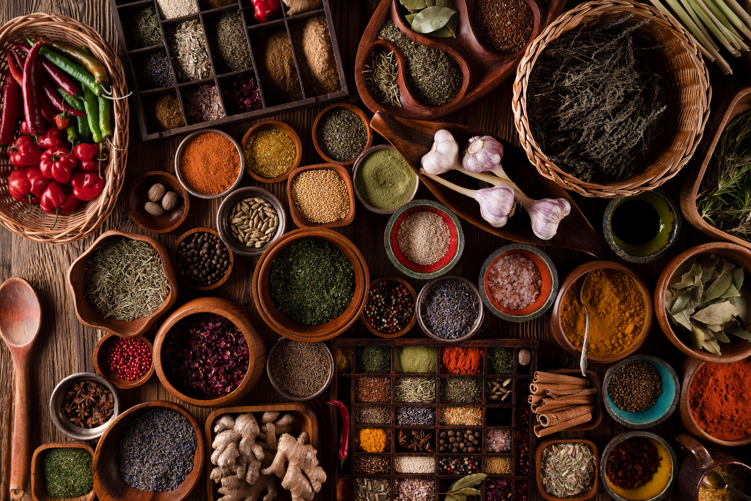 Chillies, turmeric, cardamom, cinnamon and dried herbs laid out in wooden bowls